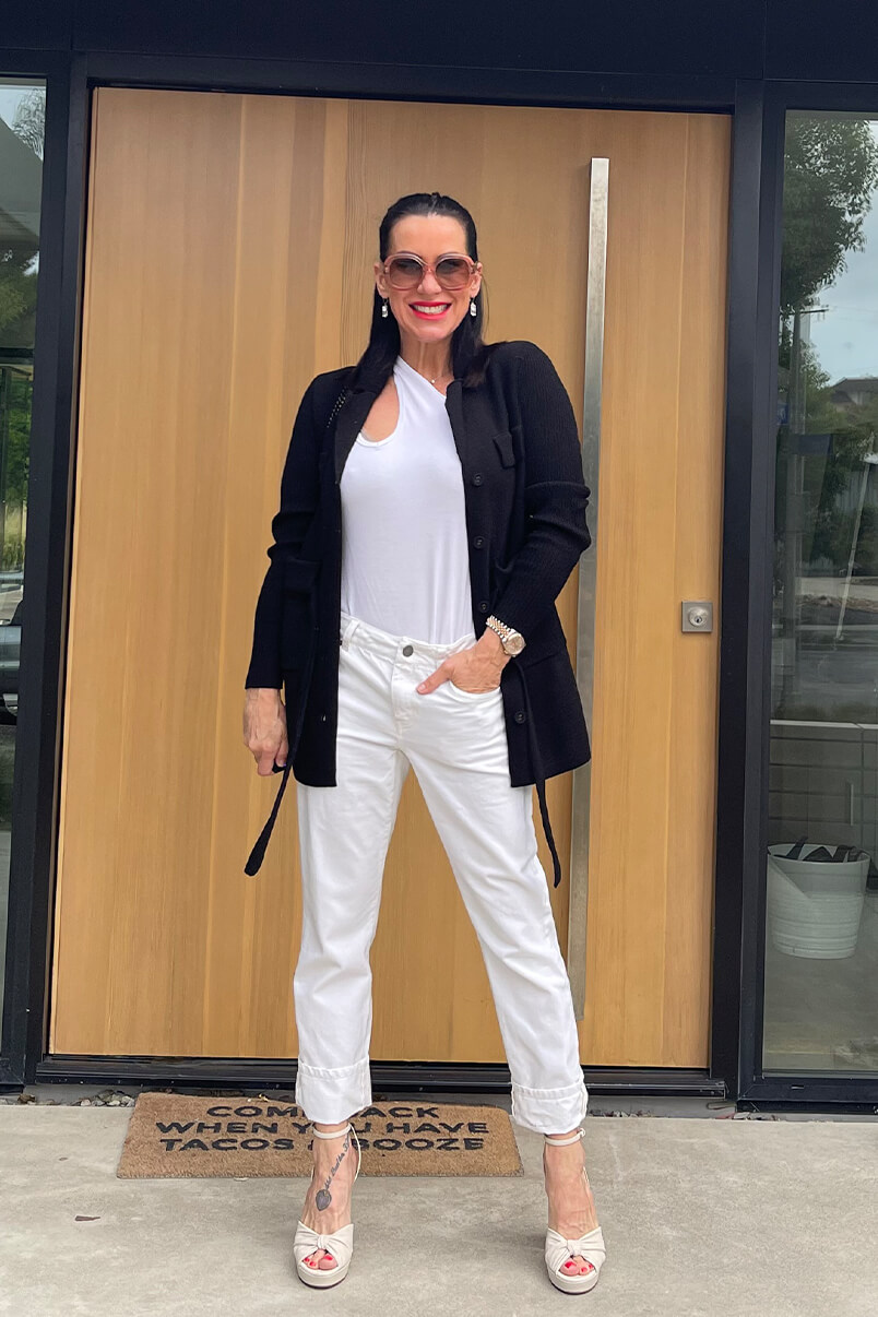 Kat Woodside, Chief Design Officer models her outfit of the day featuring the Busy Tank in Brite White, White 100% Boyfriend in Vintage White, Jackie Cardigan in Black, statement accessories and stilettos.