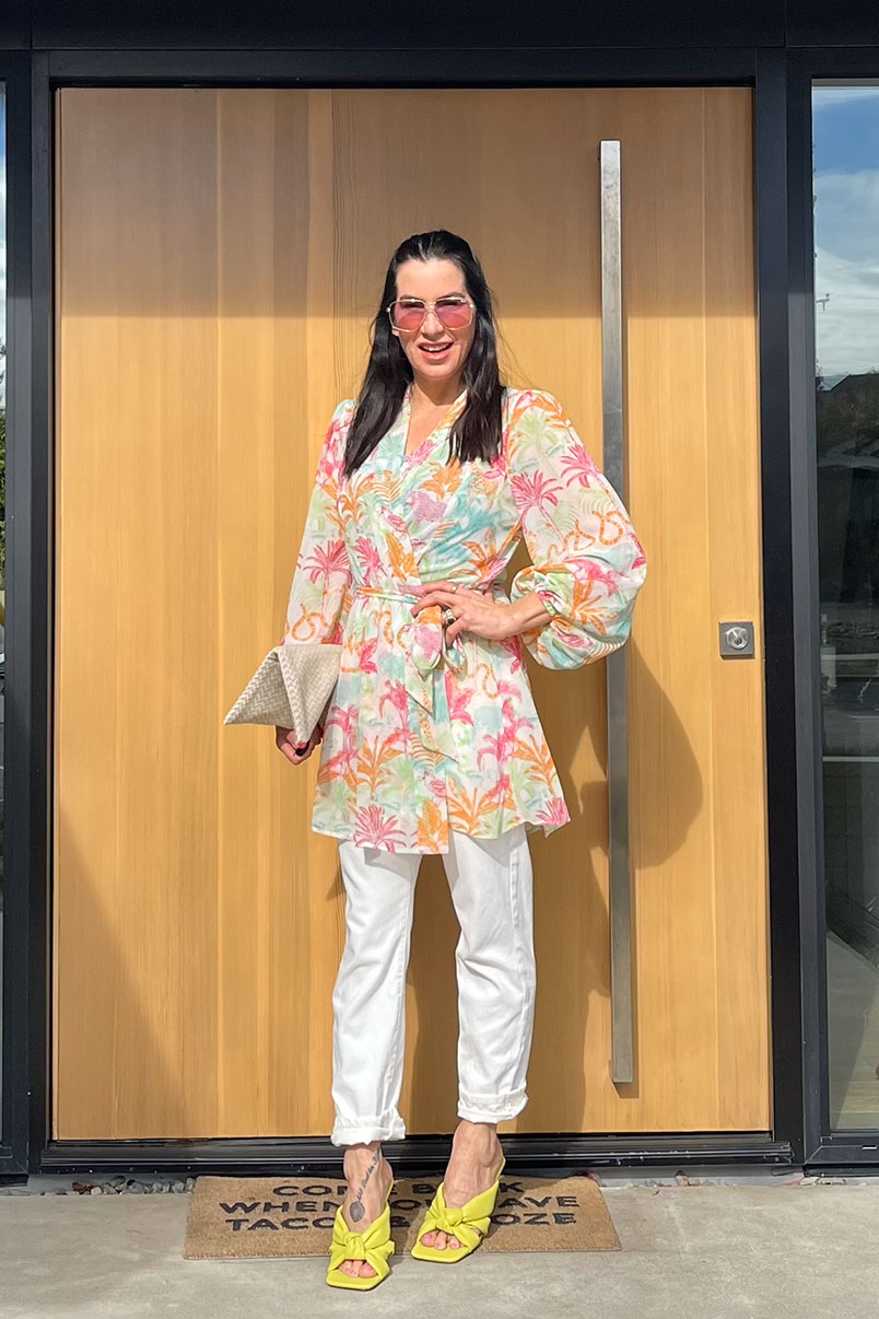 Kat Woodside, Chief Design Officer models her outfit of the day featuring the Sunset Kimono in Tropical Jungle, The Skinny in Brite White, statement accessories and heels.
